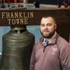 Honoree Joseph Curry standing in front of a bell with the words Franklin Town 