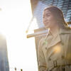 Honoree Binh Nguyen wearing a trench coat and standing in the sunlight on a downtown Philadelphia street