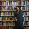 Honoree Sabriaya Shipley wearing a green dress and leaning against shelf full of books