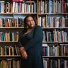 Honoree Sabriaya Shipley wearing a green dress and leaning on a bookshelves