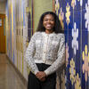 Honoree Sydney Smith smiling and leaning against a mural in the hallway of the elementary school where she teaches