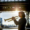 Honoree Bell Thompson playing her trumpet in front of a New York City bridge