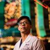 Honoree Binh Le wearing a white labcoat and standing in front of bright lights on the Las Vegas strip