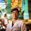 Honoree Binh Le wearing a white doctor's coat and standing in front of bright lights in Vegas