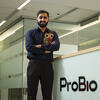 Honoree Devarshi Brahmbhatt wearing a blue button down and standing in front of the ProBio company sign