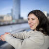 30 Under 30 honoree Andrea Behler leaning on a bridge railing overlooking a city skyline. Her hands are clasped and she's wearing a winter coat.